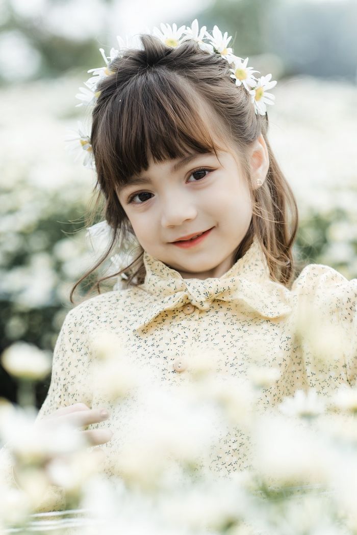 Bé gái được ví như tiểu Lisa tạo dáng đáng yêu bên hoa cúc họa mi