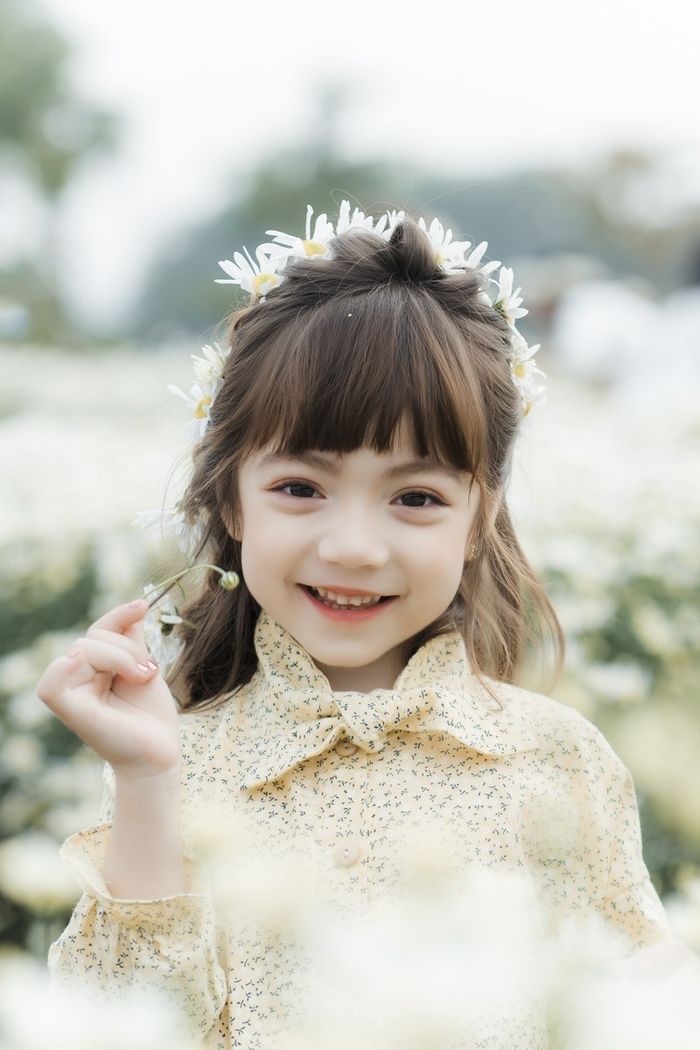 Bé gái được ví như tiểu Lisa tạo dáng đáng yêu bên hoa cúc họa mi