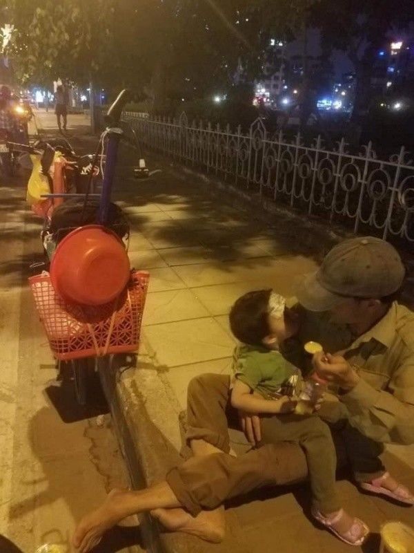 Người bố bón từng muỗng cháo cho con bên vệ đường giữa đêm lạnh
