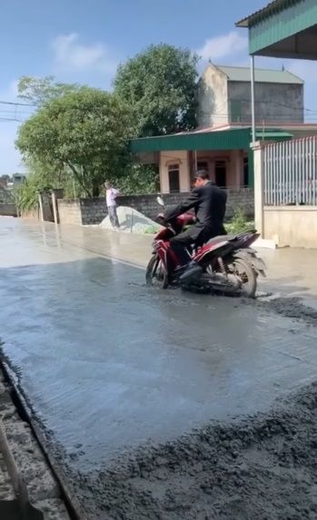 Người đàn ông chạy xe máy lên đường đang đổ bê tông
