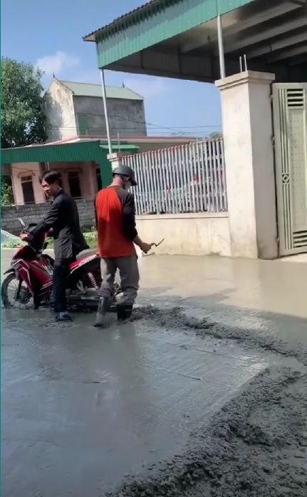 Người đàn ông chạy xe máy lên đường đang đổ bê tông