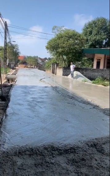 Người đàn ông chạy xe máy lên đường đang đổ bê tông