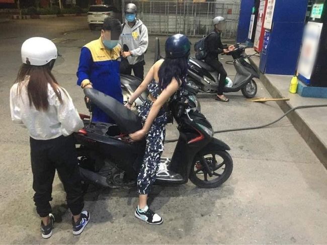 Vào đổ xăng, cô gái ngồi luôn trên yên kệ nhân viên bơm xăng loay hoay