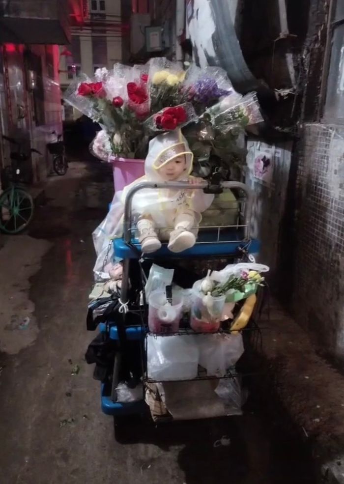 Em bé đội áo mưa đi theo mẹ bán hoa mưu sinh: Ai cũng nghẹn lòng