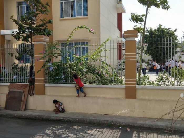 Thương cảnh hai em bé đứng nhìn qua khe cửa trước cổng trường