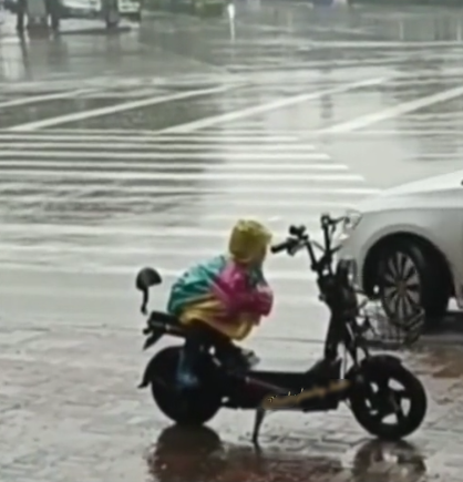 Trời mưa tầm tã, em bé luýnh quýnh nhướn người che chắn yên xe cho bố