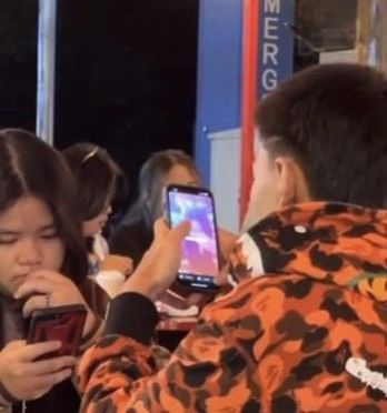 Ngồi trên bàn ăn, chàng trai cầm điện thoại lén chụp ảnh người yêu